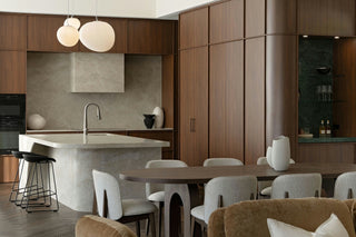 Luxury St Peters Display Home kitchen with curved fluted island bench, walnut cabinetry, stone splashback and modern pendant lighting in open-plan design.